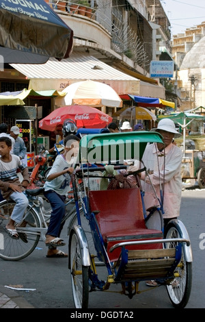 Un homme pousse un cyclo sur une rue de ville de Phnom Penh, Cambodge. Banque D'Images