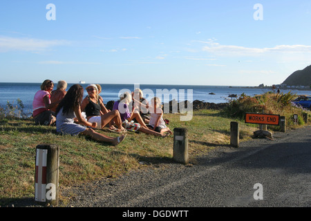 Les personnes ayant des aires de pique-nique près de la plage sur une journée ensoleillée au cours de la période de congé annuel de vacances /, avec 'fonctionne' panneau routier à proximité. Banque D'Images