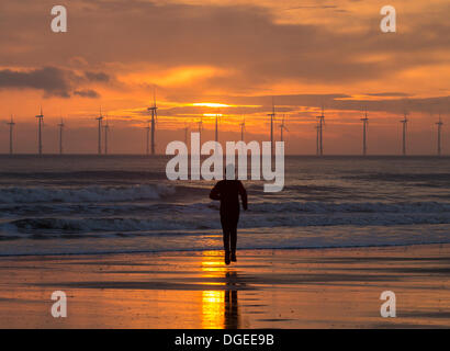 Jogger sur Seaton Carew au lever du soleil plage parc éolien offshore de withTeesside à Redcar en distance Banque D'Images