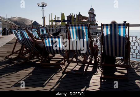 Les gens dans des chaises longues sur la jetée de Brighton, Sussex, UK Banque D'Images