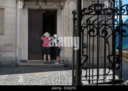 Deux femmes à travers la porte à l'église de Saint Vigilio à Gandria, sur les rives du lac de Lugano. Le tessin. La Suisse Banque D'Images