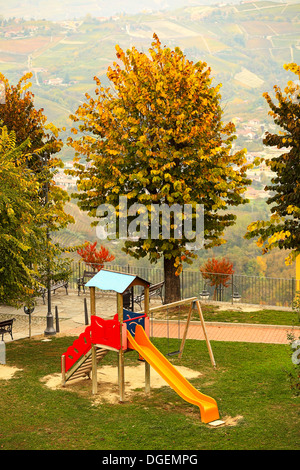 L'enfant solitaire faites glisser sur l'aire vide en automne dans la petite ville de Diano d'Alba, Italie. Banque D'Images