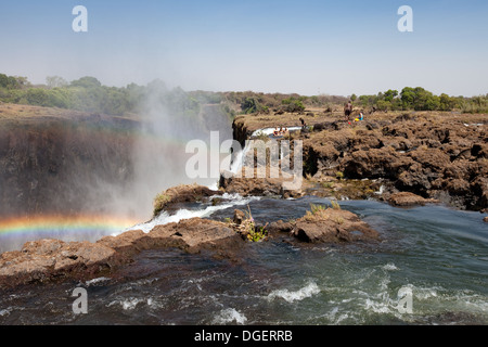 Le bord des chutes Victoria avec rainbow et la natation de personnes dans la région de Devils extérieure dans la distance, la Zambie Afrique du Sud Banque D'Images