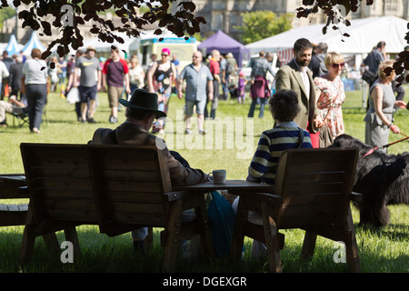 Couple ayant pause boisson dans l'ombre les visiteurs marchent autour de sex jeu sunny Country Fair 2013 Burghley House Stamford Angleterre Banque D'Images