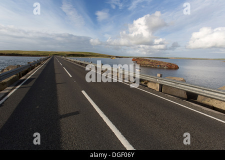 Des îles Orcades, en Écosse. L'A961 à barrière Churchill numéro 3 avec un blockship engloutie dans l'arrière-plan. Banque D'Images