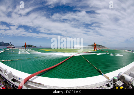 Les membres d'équipe de forage d'huile contrôle de la ligne de canons à mousse pont d'atterrissage de l'hélicoptère à l'OCEAN RIG MYKONOS navire de forage. Banque D'Images