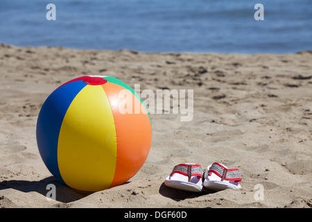 Ballon de plage et tongs sur la plage avec la mer en arrière-plan et l'espace de copie dans la partie supérieure de l'image Banque D'Images