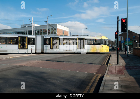 Tramway Metrolink sur l'Est, traversant la ligne de Manchester Ashton Nouveau Road, Clayton, Manchester, Angleterre, RU Banque D'Images