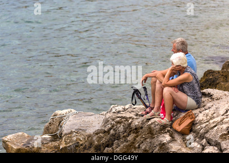 Couple mature au bord de la mer, en prenant une pause de la marche Korcula Croatie Banque D'Images