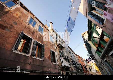 Comité permanent des maisons proches les unes des autres avec des vêtements sèchent sur des cordes tendues entre eux, Castello, Venise, Venise, Vénétie, Italie Banque D'Images