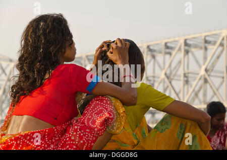 Jeune femme à la recherche des poux dans les cheveux d'une autre femme, en face de Howrah Bridge, Kolkata, Inde, Asie Banque D'Images