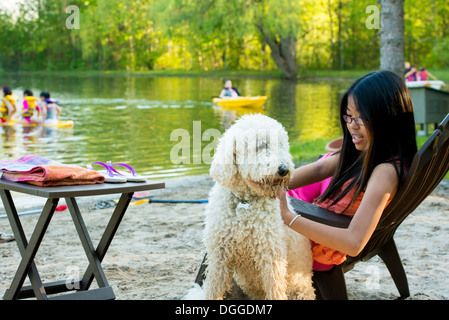 Girl sitting on chair par le lac avec chien Banque D'Images