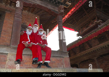 Trois hommes en père Noël assis sur les marches du temple à Durbar Square, Vallée de Katmandou, Katmandou Banque D'Images