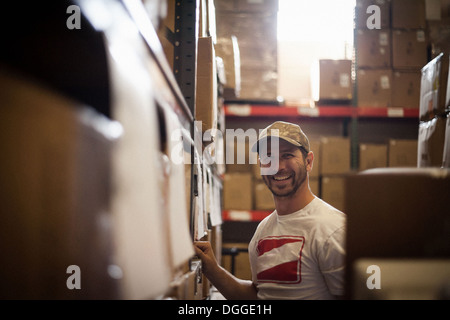 Travailleur et boîtes de carton stocké dans warehouse Banque D'Images