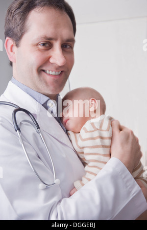 Young doctor holding baby boy, portrait Banque D'Images