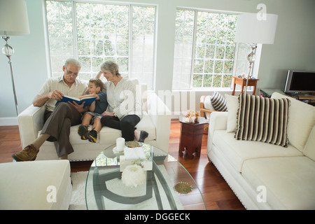 Les grands-parents montrant boy album photo sur canapé Banque D'Images