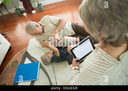 Petit-fils de chatouillement Senior man on rug Banque D'Images