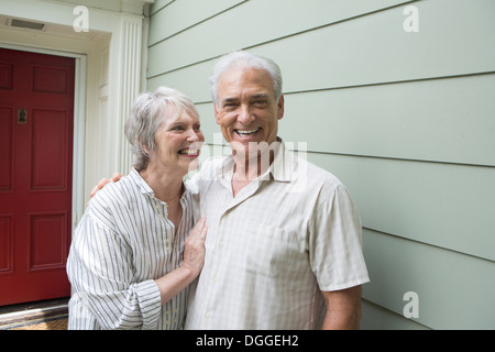 Senior couple smiling together outside house, portrait Banque D'Images