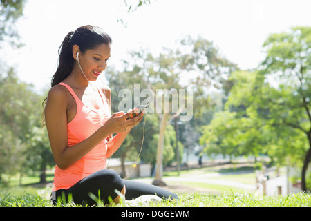 Young woman listening to mp3 player in park Banque D'Images