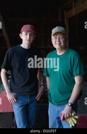 Agriculteur à maturité et son fils dans une grange, portrait Banque D'Images