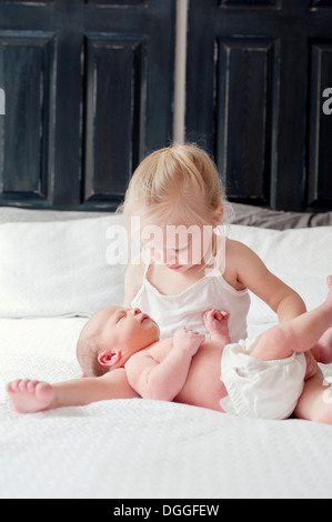 Girl sitting on bed with baby brother Banque D'Images