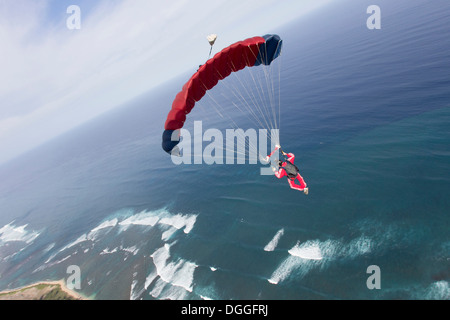 Parachutiste avec parachute rouge au-dessus de Honolulu, Hawaii Banque D'Images