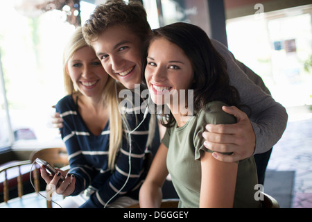 Groupe d'amis qui partagent des écouteurs dans coffee house Banque D'Images