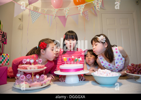 Girls blowing out birthday candles on cake Banque D'Images