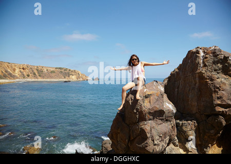 Jeune femme assise sur des rochers, Palos Verdes, California, USA Banque D'Images