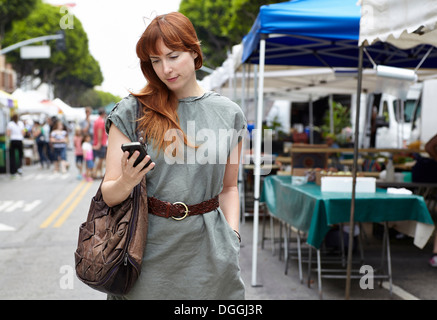 Mid adult woman looking at mobile phone in city Banque D'Images