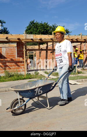 Femme des bidonvilles, favelas, poussant une brouette sur un chantier de construction de la "Esperança" housing co-operative, chaque famille Banque D'Images