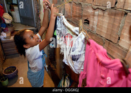 Girl étendre le linge sur une corde dans un taudis ou favela, Ananindeua favela, Rio de Janeiro, Rio de Janeiro, Brésil de l'État Banque D'Images