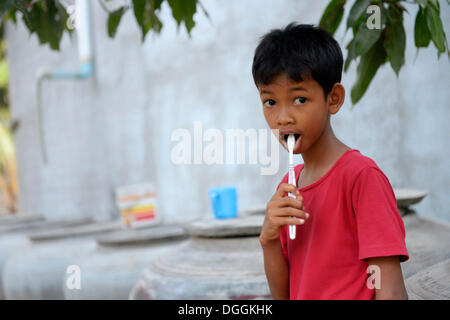 Jeune garçon se brosser les dents à l'extérieur une maison Lompong, commune, district, Province de Takéo Bathi, Cambodge Banque D'Images