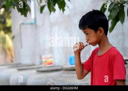 Jeune garçon se brosser les dents à l'extérieur une maison Lompong, commune, district, Province de Takéo Bathi, Cambodge Banque D'Images