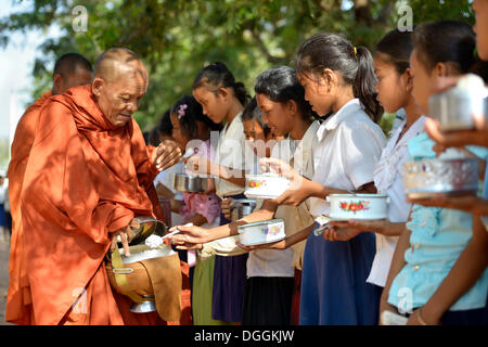 Les enfants donnant de la nourriture et de l'argent à un moine bouddhiste, cérémonie traditionnelle dans le cadre de la célébration du nouvel an cambodgien Banque D'Images