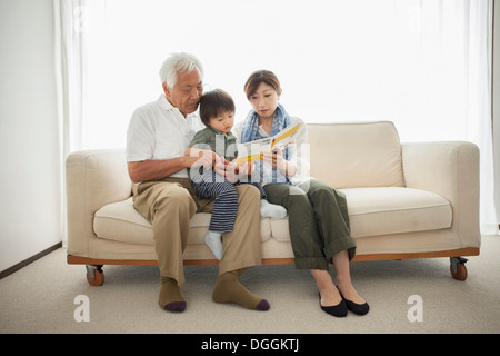 Lecture de la mère en fils assis sur les genoux de grand-père Banque D'Images