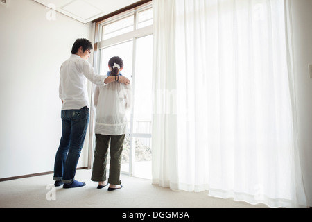 Couple standing by window Banque D'Images