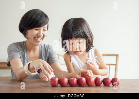 Mère et fille avec des pommes rouges dans une rangée Banque D'Images