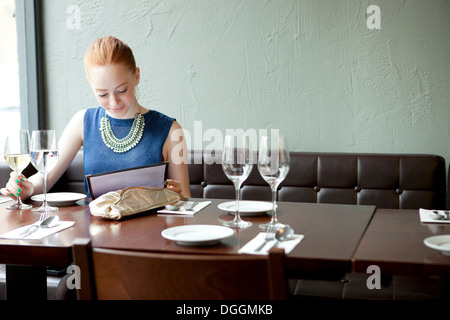 Jeune femme au restaurant, menu de lecture Banque D'Images