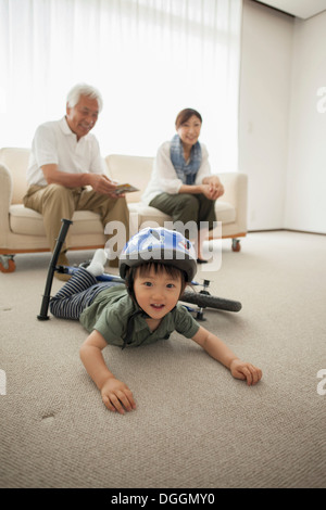 Boy lying on floor with bicycle Banque D'Images