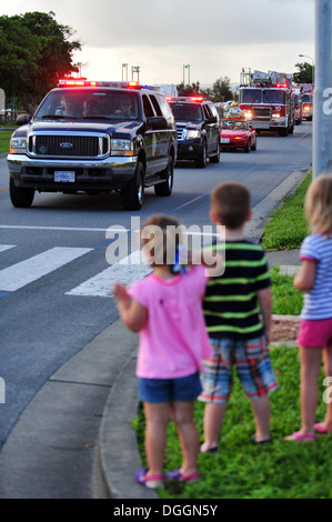 Regardez les enfants en tant que membres du 18e Escadron de génie civil en voiture dans la rue pendant le défilé de la Semaine de prévention des incendies sur Kadena Air Base, Japon, Octobre 09, 2013. Le Ministère a dirigé l'incendie Kadena parade dans le logement de base tout en jetant des bonbons à cro Banque D'Images