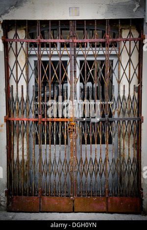 Type accordéon portes en métal rouillé verrouillé en face d'une paire de portes. Banque D'Images