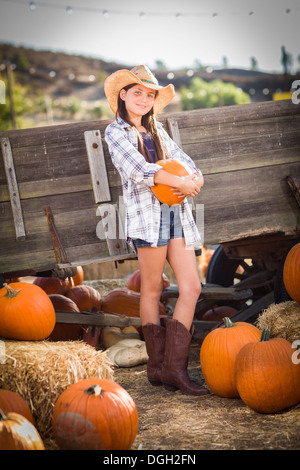 Preteen Girl Wearing Cowboy Hat Portrait à la citrouille dans un cadre rustique. Banque D'Images