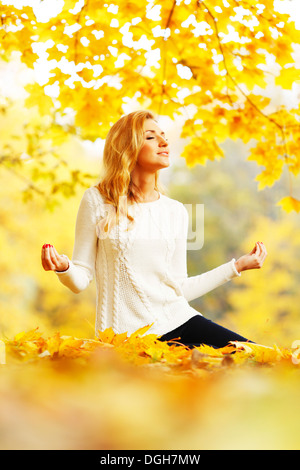 Beautiful young woman meditating outdoors in autumn park Banque D'Images