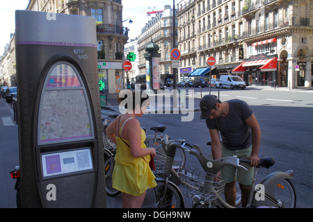 Paris France,2ème arrondissement,rue des filles Saint-Thomas,Velib vélo partager système,homme hommes,adulte,femme femme,couple,prendre vélo Banque D'Images