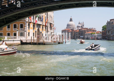 Un bateau à moteur chefs sous un pont le long du Grand Canal vers l'église Santa Maria della Salute, Venise, Italie, Europe Banque D'Images