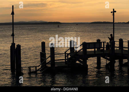 Le port de Poole, Dorset. Coucher du soleil sur l'eau pour les collines de Purbeck avec jetée sur pêcheur Banque D'Images