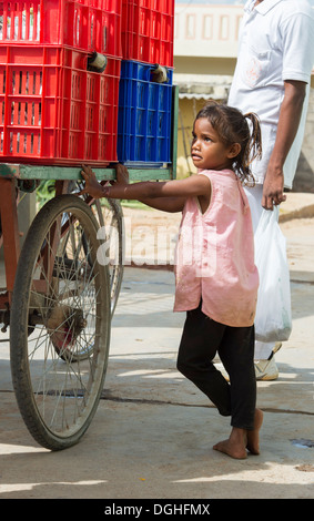 Basse caste indien Girl standing by un tricycle de boîtes contenant des paquets de nourriture. Puttaparthi, Andhra Pradesh, Inde Banque D'Images