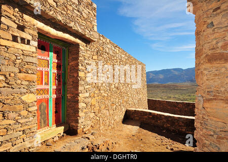 Des murs en pierre naturelle, maison avec une porte en bois coloré, Tizourgane, Marrakech-tensift-Draâ, Antiatlas, Maroc Banque D'Images