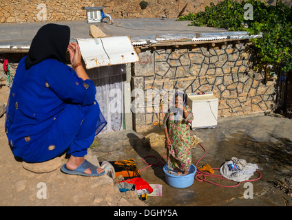 Laver les vêtements des femmes dans l'ancien village kurde de Palangan au crépuscule, l'Iran Banque D'Images